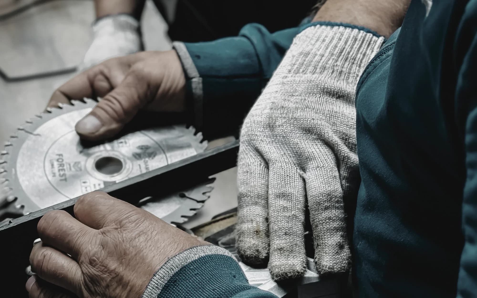 Handwerker mit Arbeitshandschuhen prüft in einer Werkstatt ein Kreissägeblatt
